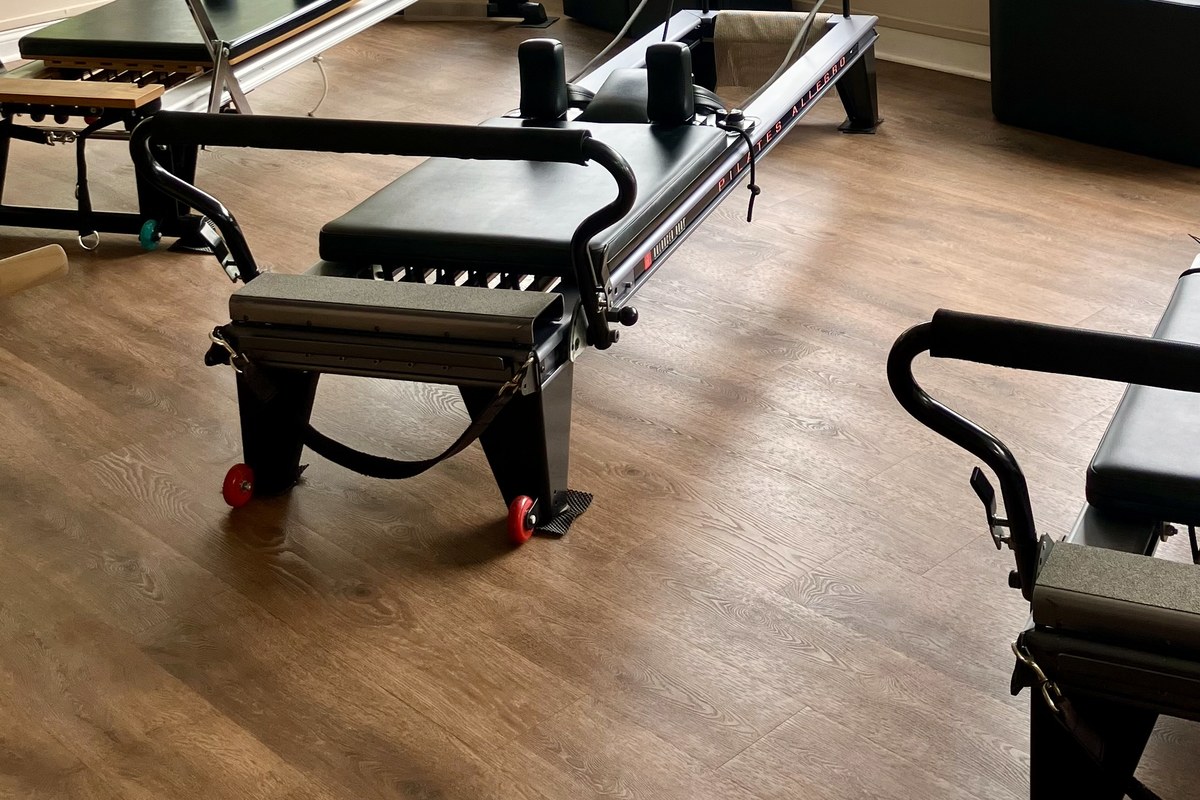 A reformer carriage, footbar and rails on the studio wood floor.